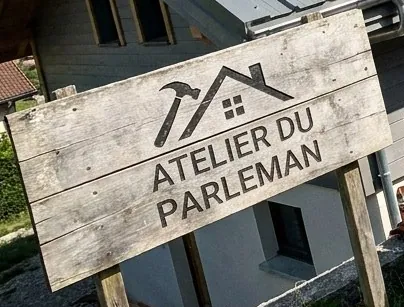 Panneau en bois de l'Atelier du Parleman planté devant un chantier de couverture à Dingy-Saint-Clair